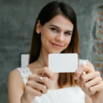 Seorang perempuan tersenyum memegang kartu keanggotaan sebagai ilustrasi program member dan loyalitas pelanggan